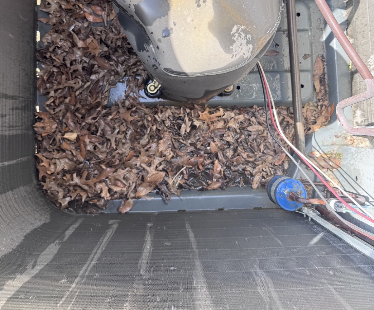 Air conditioner condenser full of leaves before cleaning in Prosper, TX