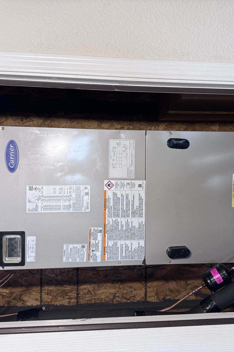 Carrier air handler installed in a utility closet during a heat pump installation in Celina, TX, with the electrical disconnect, data plate and sealed plenum connection