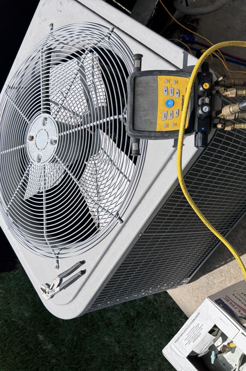 Emergency AC repair call in Celina, TX — Fieldpiece digital manifold reading live system pressures at the condenser, with hoses connected and R-410A refrigerant on site