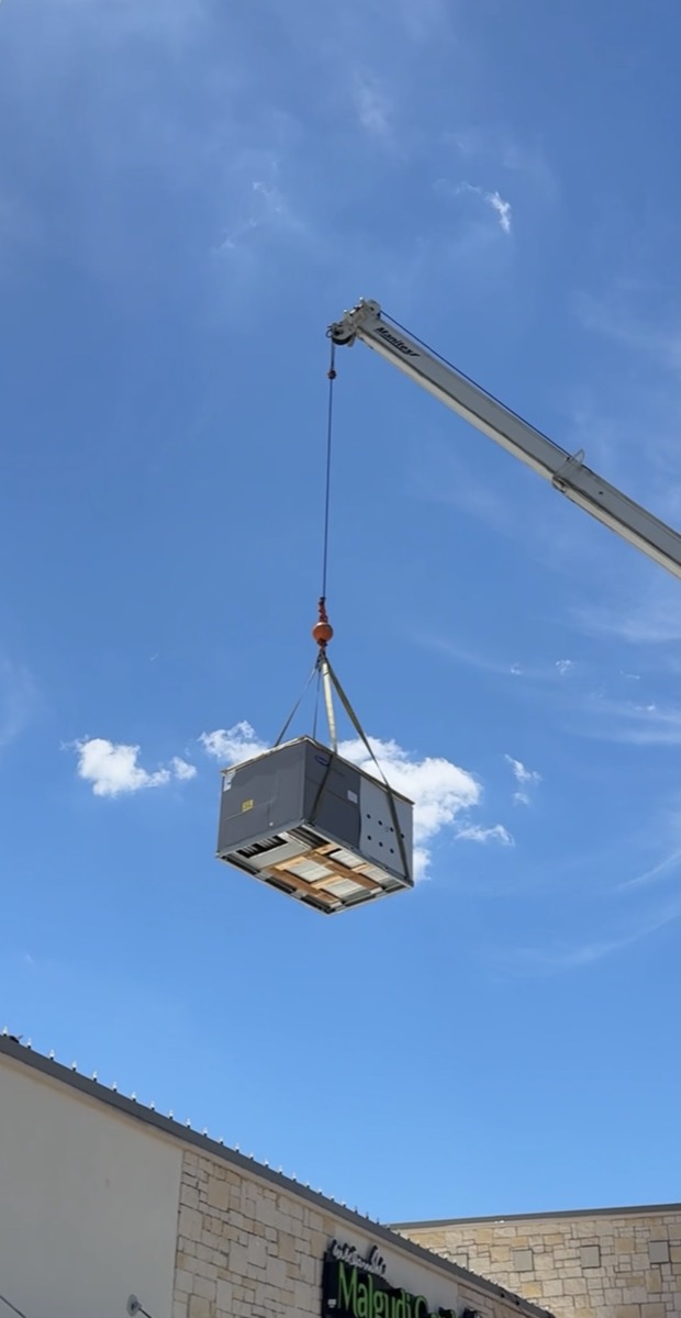 Crane lifting a commercial rooftop HVAC unit into place during an RTU replacement by Panda Heating and Cooling